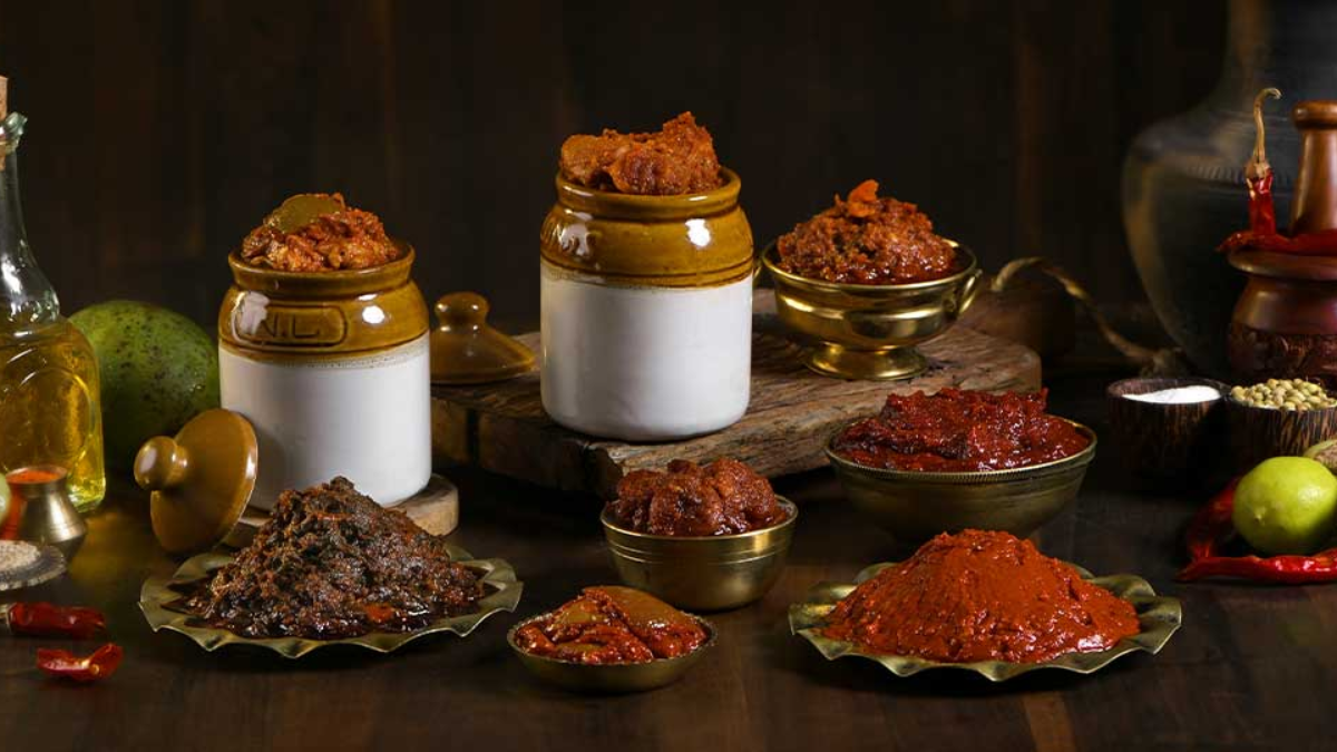 A variety of colorful pickles and chutneys in glass jars.